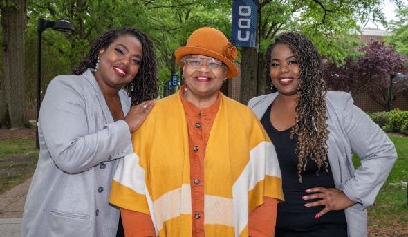 Twin sisters standing on either side of their mother.